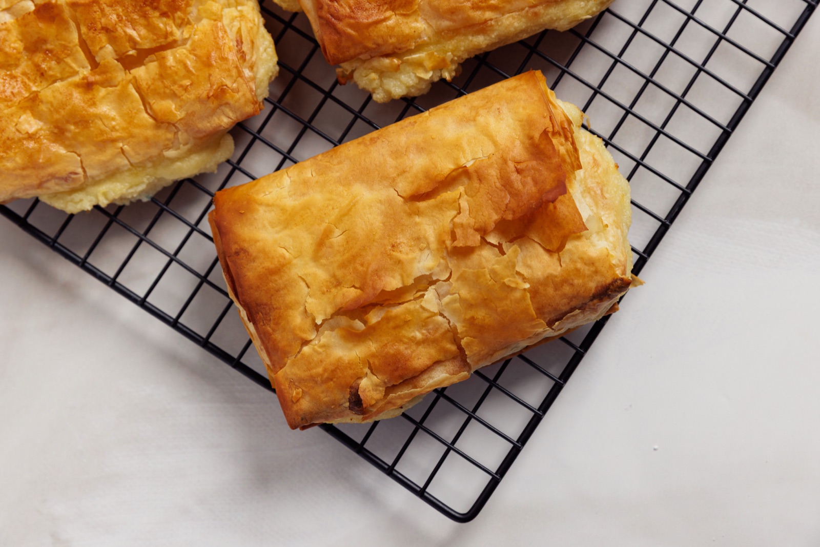 Freshly baked golden bougatsa parcels resting on a cooling rack
